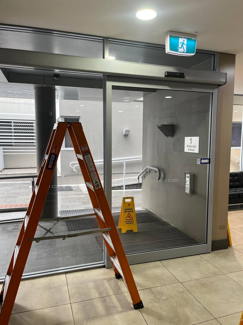 NEWGEN technician servicing a commercial automatic door at a Sydney CBD building entrance