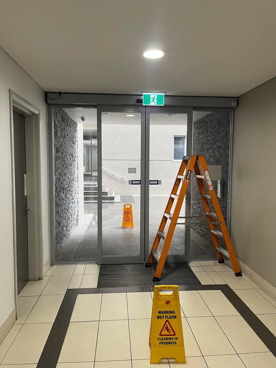 Technician working on a commercial automatic sliding entry door at a business premises in Sydney